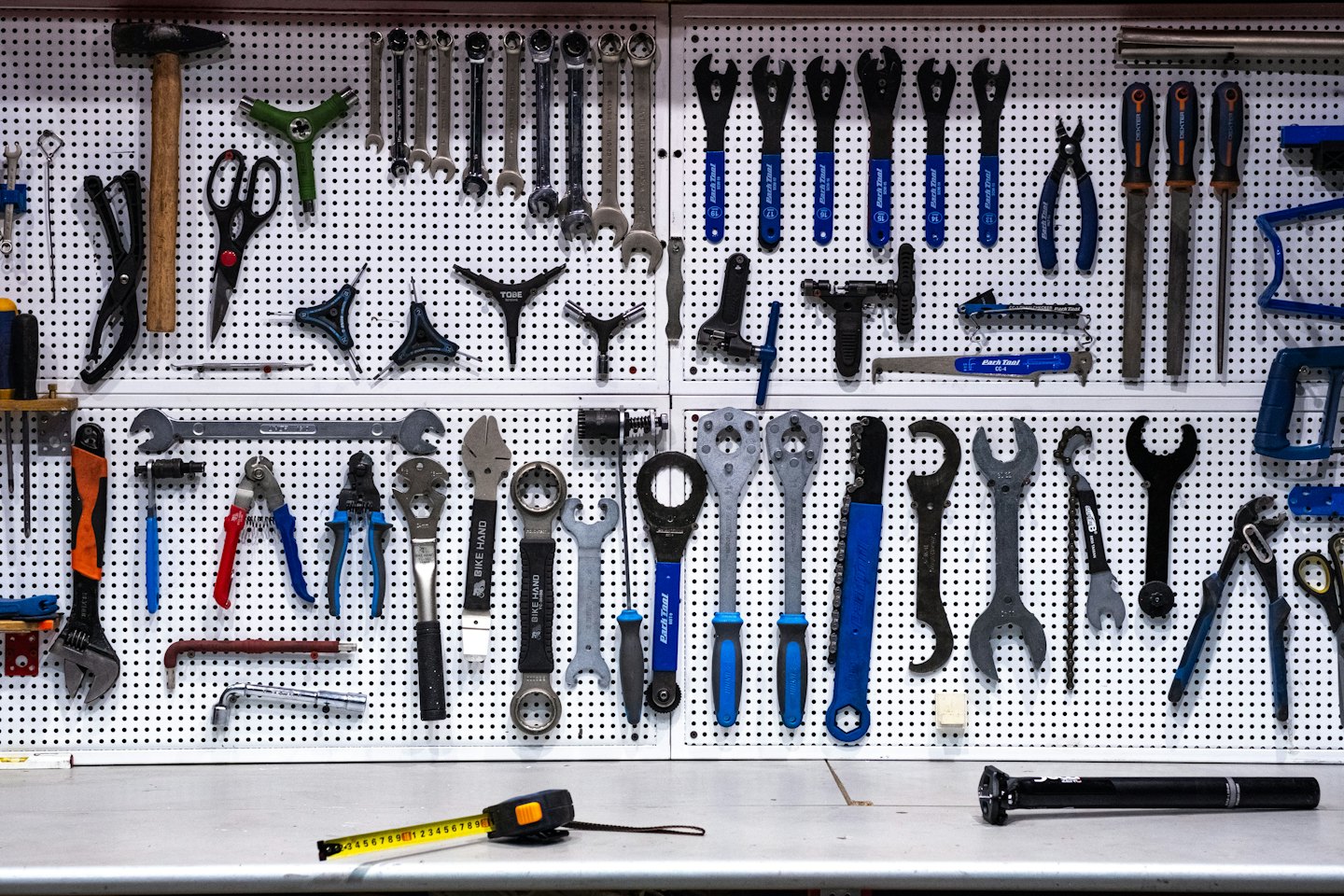 A pegboard displays an organized collection of bicycle repair tools.