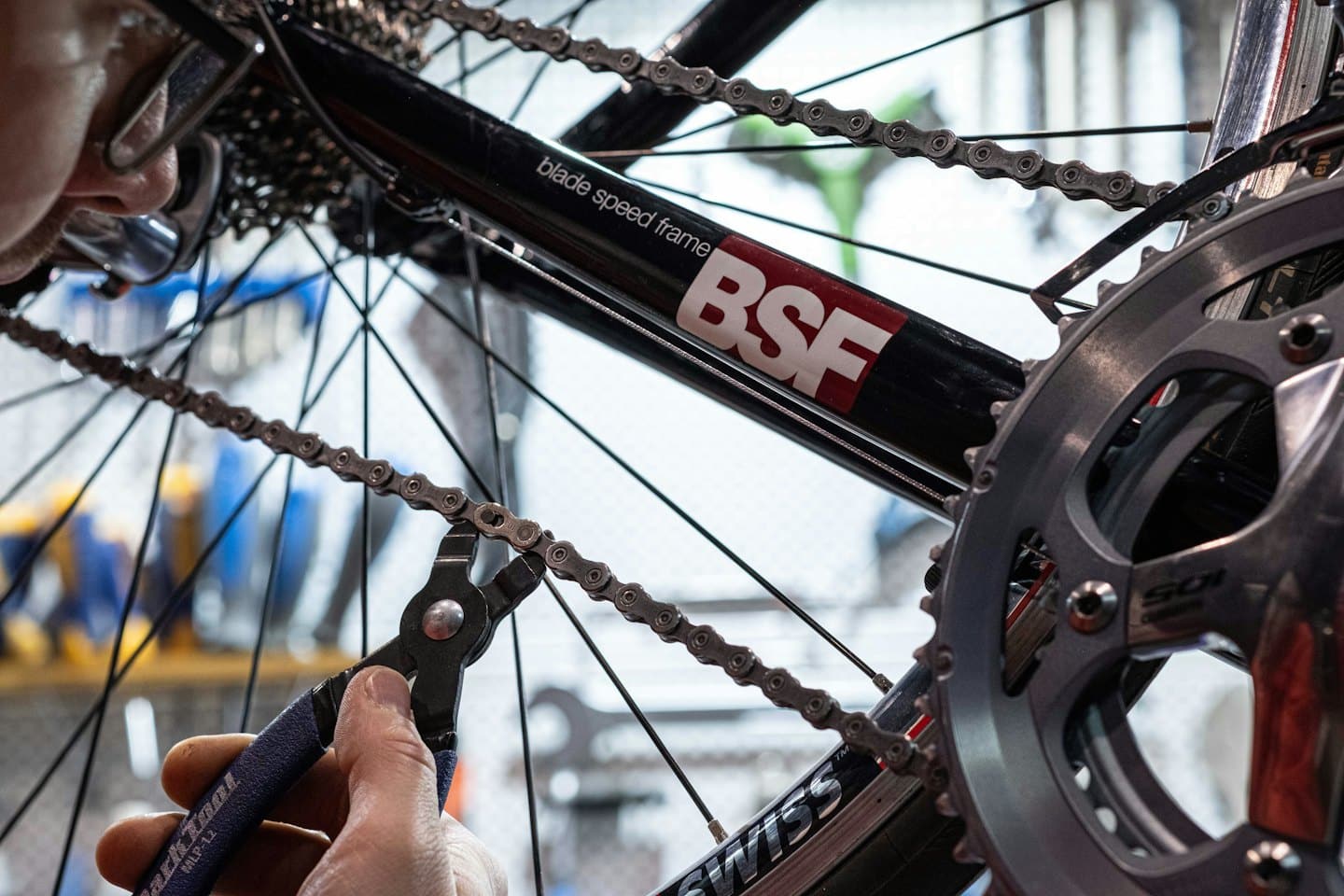 Mechanic uses a tool to repair a bicycle chain.